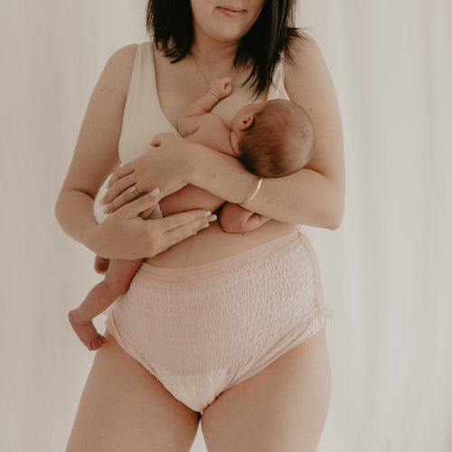 Woman holds newborn in partum panties disposable underwear for women in pregnancy and postnatal
